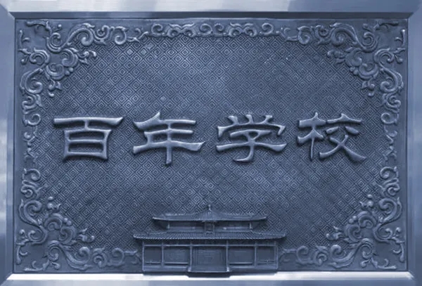 灯市口小学百年学校石雕牌匾实景照片，雕花边框百年学校字样，校园文化环境建设