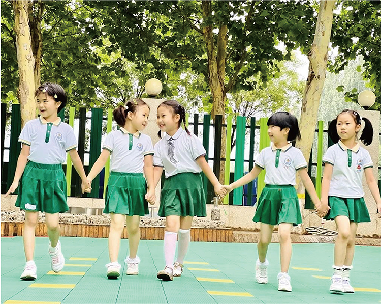 北部新区实验幼儿园女孩们身着绿白园服户外手拉手围圈的活动照片,校园特色