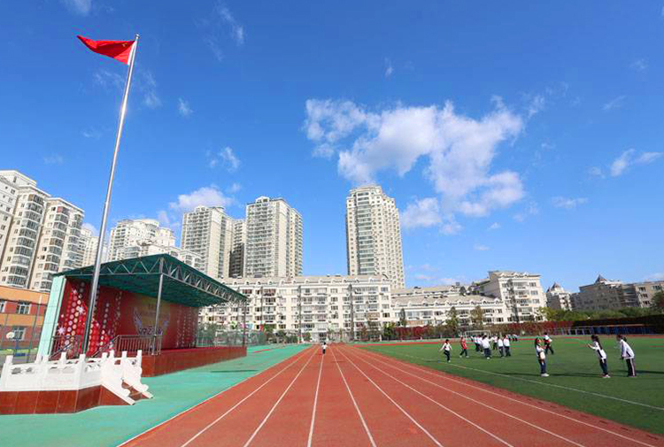 灯市口小学操场实景照片，旗杆红旗与跑道楼宇，校园环境与特色定位展示