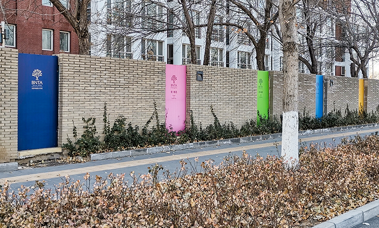 新英才学校室外粉绿橙彩色文化导视立柱实景，锦连环校园导视系统设计