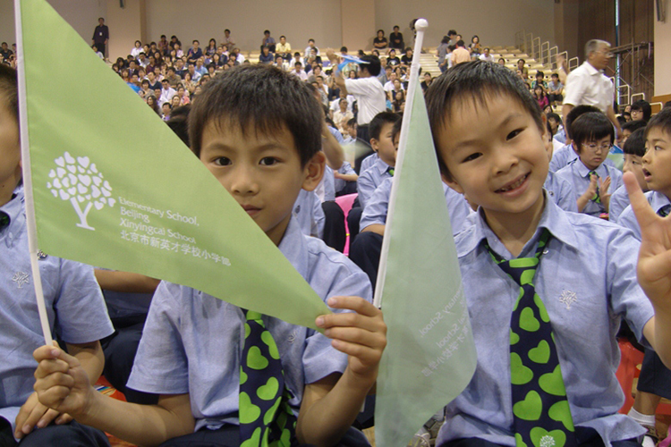 新英才学校学生手持绿色旗帜参加活动实景，锦连环学校文化建设