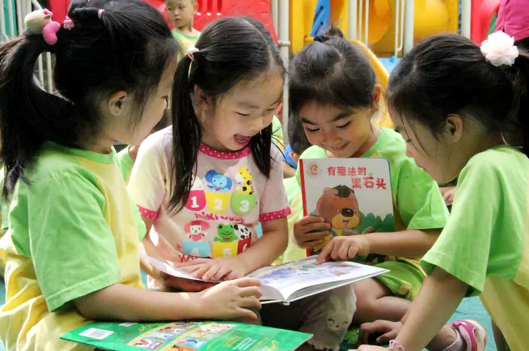 五色土幼儿园孩子们身着绿色园服围坐看绘本实景，锦连环园所文化建设