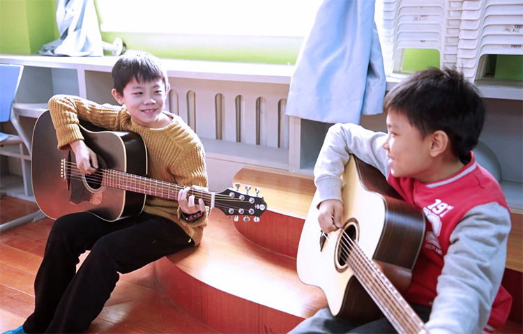 灯市口小学教师与学生弹吉他互动场景，锦连环学校文化建设