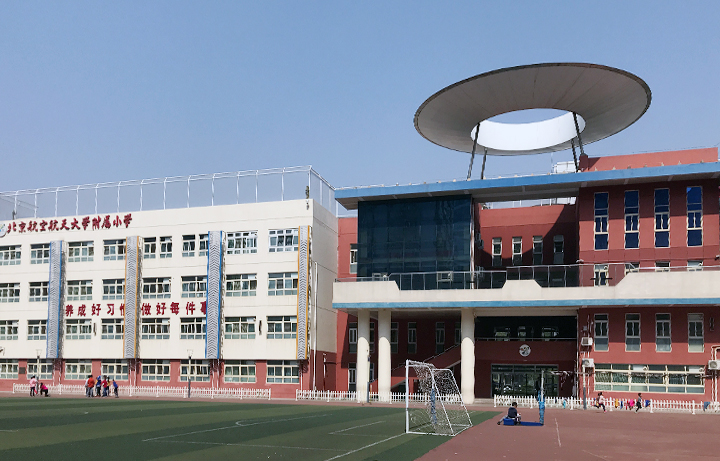 北京航空航天大学实验学校小学部教学楼实景，红砖建筑与绿茵操场，校园环境建设
