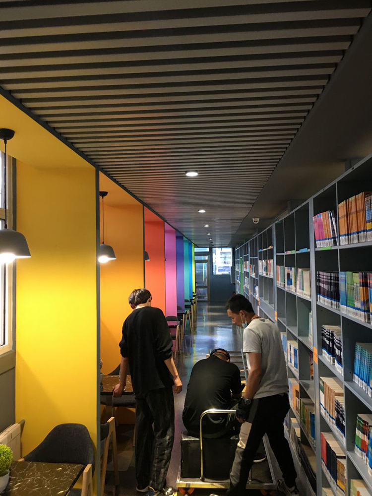 锦连环摄制团队在红英小学图书馆书架走廊架设设备拍摄，校园文化视频制作花絮