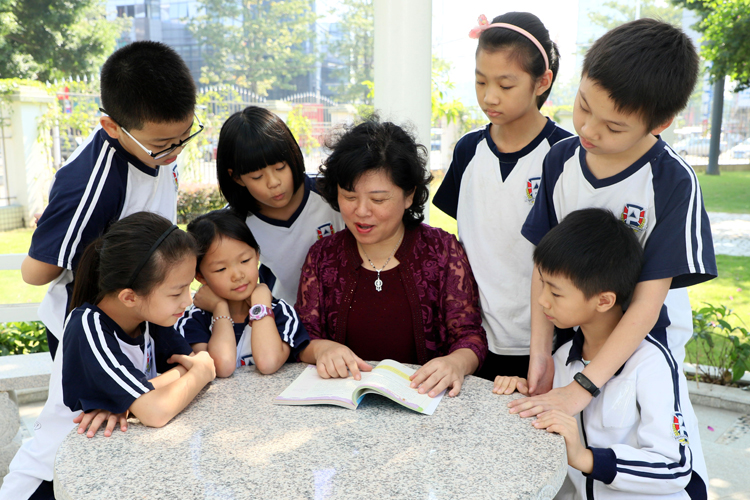 波利亚外国语学校教师与学生在户外围坐共读的校园生活场景