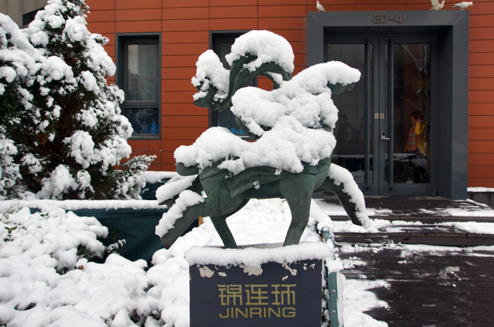 锦连环公司门前覆雪的石狮雕塑,基座印有锦连环JINRING标识的冬日实景
