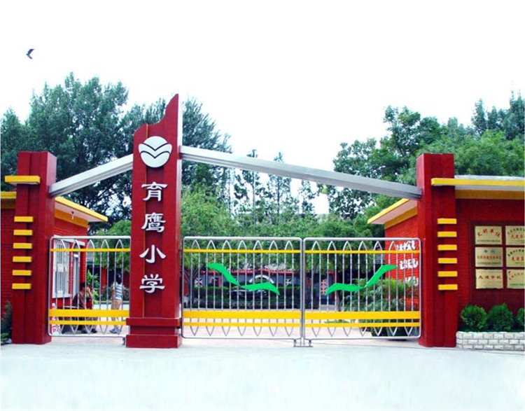 北京市海淀区育鹰小学校门实景，红色立柱校牌与校园环境建设外观