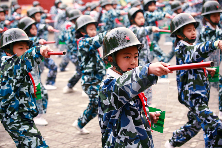 育鹰小学学生穿迷彩服参加军事拓展活动，展现国防教育课堂场景