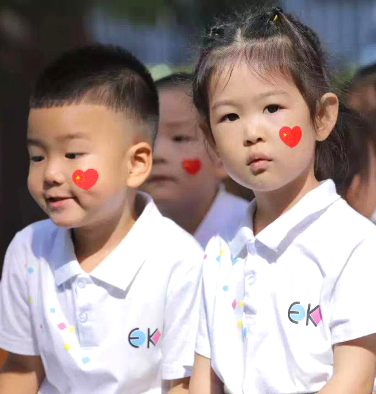 两名幼儿身穿恩济里幼儿园EK园服，脸贴爱心贴纸，展现园所品牌文化氛围