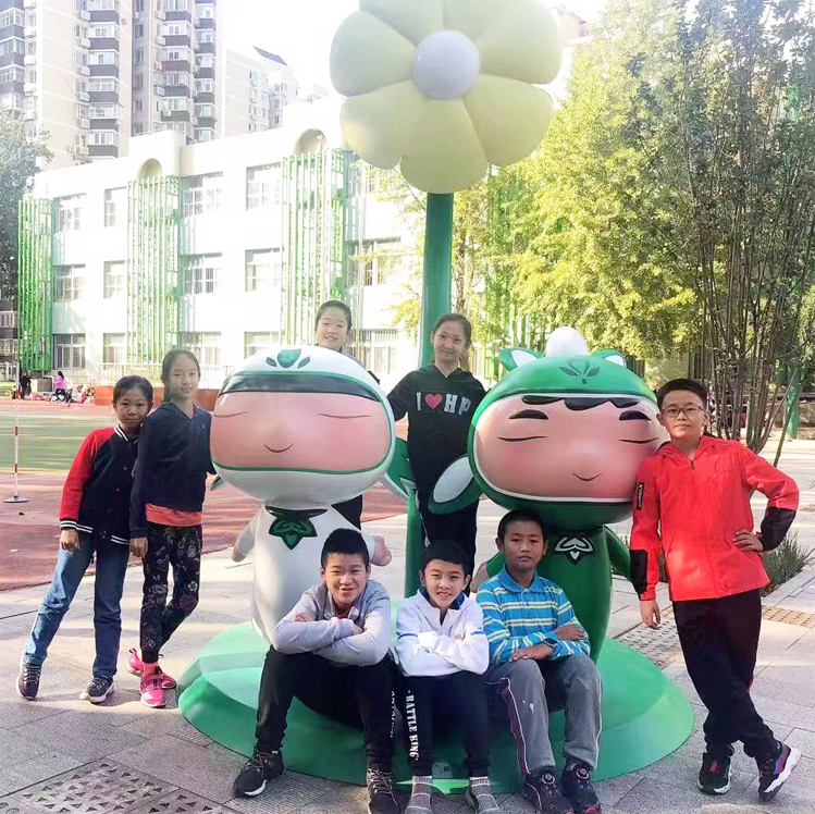 学生在北医附小校园与吉祥物雕塑合影留念,独具特色校园文化建设场景