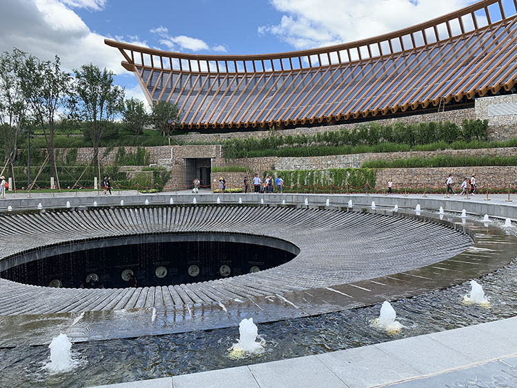 世园会环形屋檐场馆与下沉式庭院，弧形建筑环抱中心水景，造型舒展大气