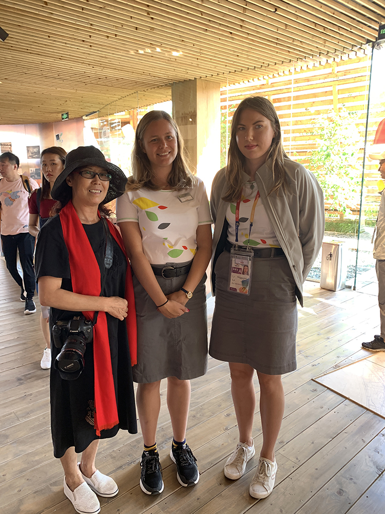 世园会内三位身着民族服饰的国际游客留影，脸绘花纹，洋溢节日气氛