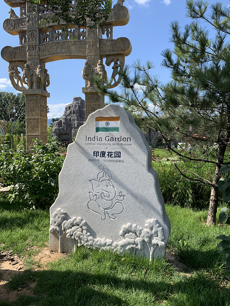 世园会印度花园入口景石，雕花石碑立于绿草间，标示展园身份