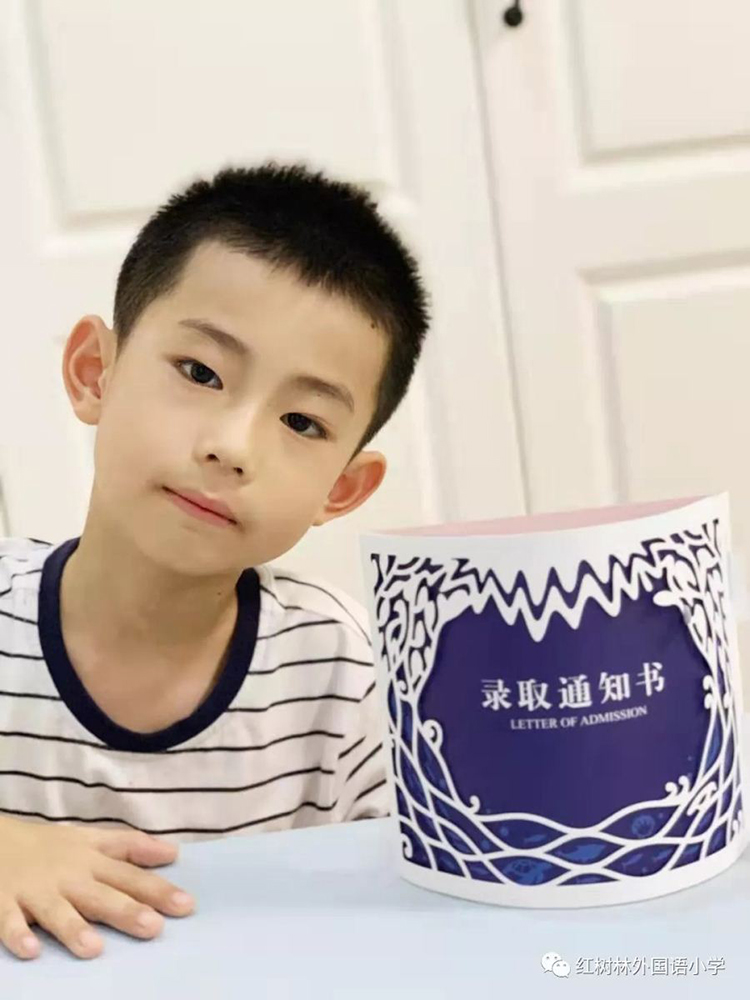 一名男孩手持红树林外国语小学录取通知书在门前合影