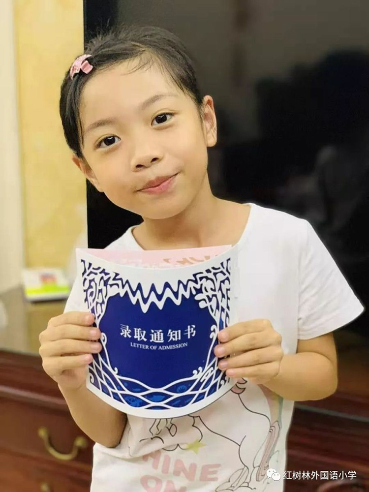 一名女孩手捧红树林外国语小学红色录取通知书的近照