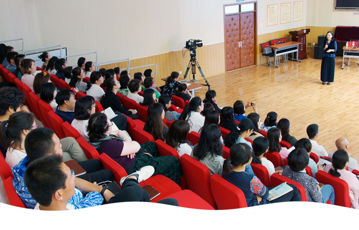 清河第四小学报告厅集会场景,学生坐在红色座椅聆听讲座,讲台上教师授课,展现校园文化活动