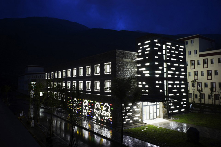 同一所学校教学楼夜景，立面点阵灯光发亮倒映水面，呈现校园建筑的光影设计