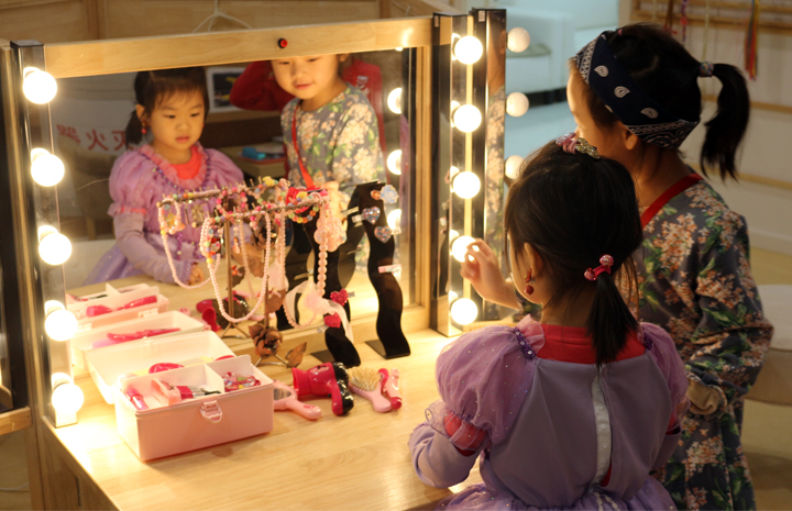 立新幼儿园角色扮演区，小朋友在亮灯化妆镜前挑选饰品体验装扮