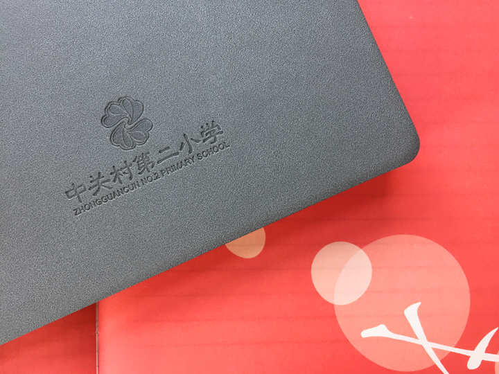 中关村第二小学定制精装笔记本，灰色封面烫印校徽校名，置于红色背景彰显校园品牌