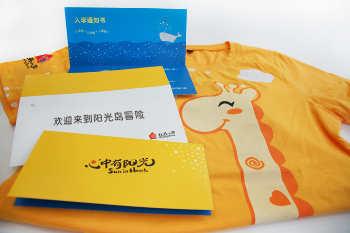 红英小学橙色系文化手册与文件夹铺陈，封面印有阳光岛标识，体现教育品牌设计统一性
