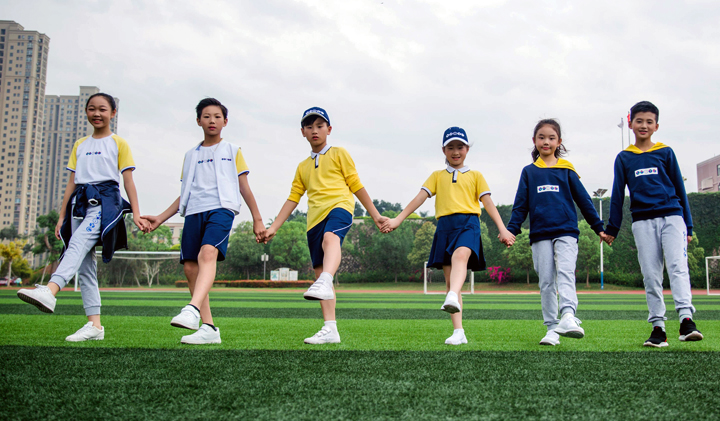 厦门英才学校学生身着校服在操场上手拉手微笑，展现校园活力与教育品牌建设的育人成果