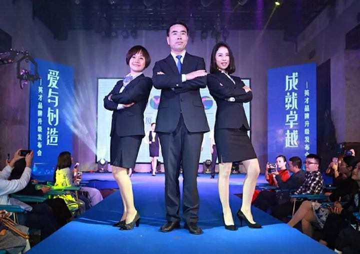 三位主持嘉宾站在厦门英才学校发布会蓝色舞台上，背景印有品牌升级主题，主持隆重发布仪式
