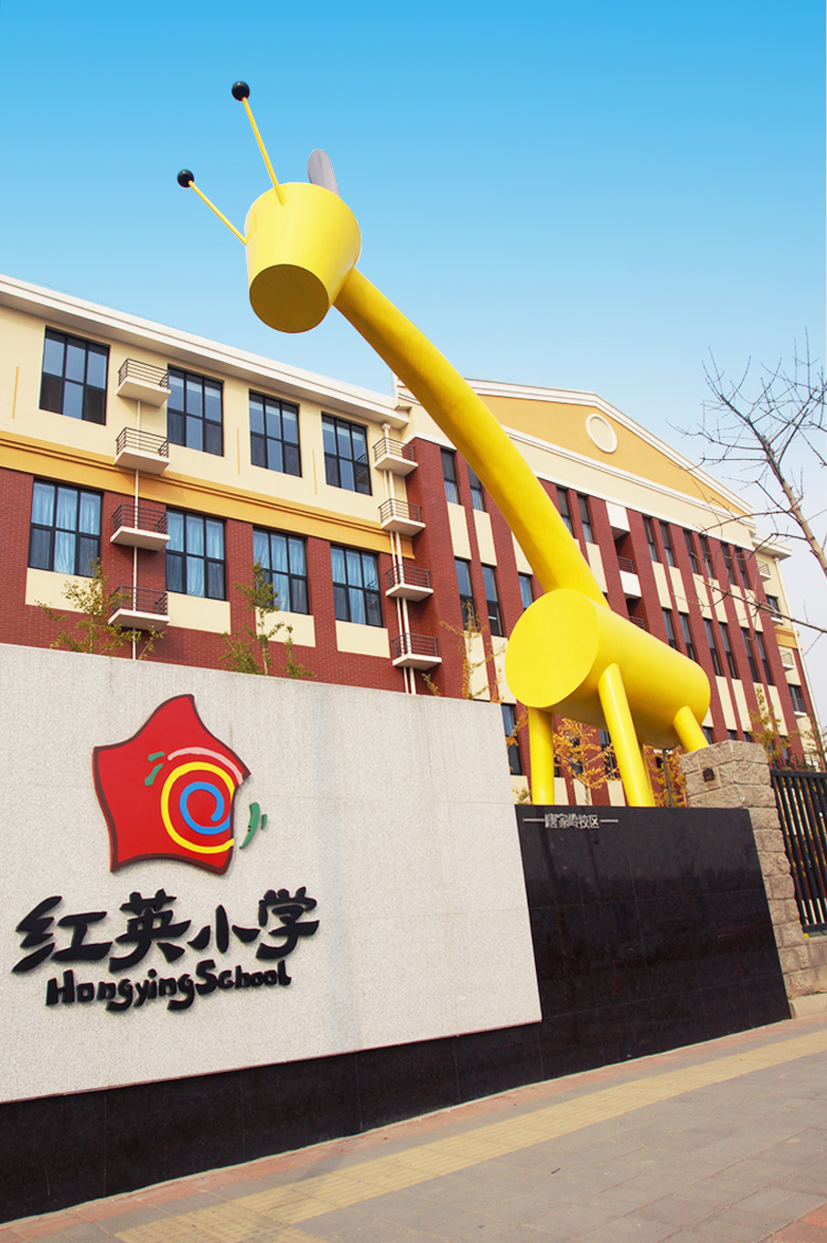 北京市海淀区红英小学建筑外观，黄色长颈鹿雕塑与红英小学标志相伴，传递心中有阳光理念