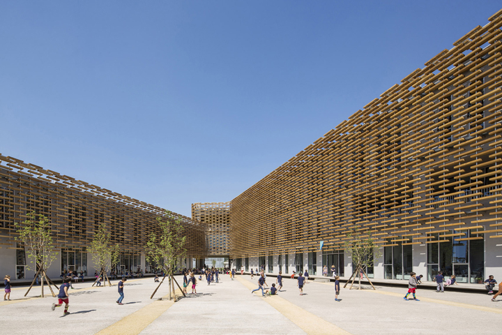 北京法国国际学校木格栅立面建筑外景,原木隔栅环绕校园广场,体现学校环境建设的灵动与节能环保理念