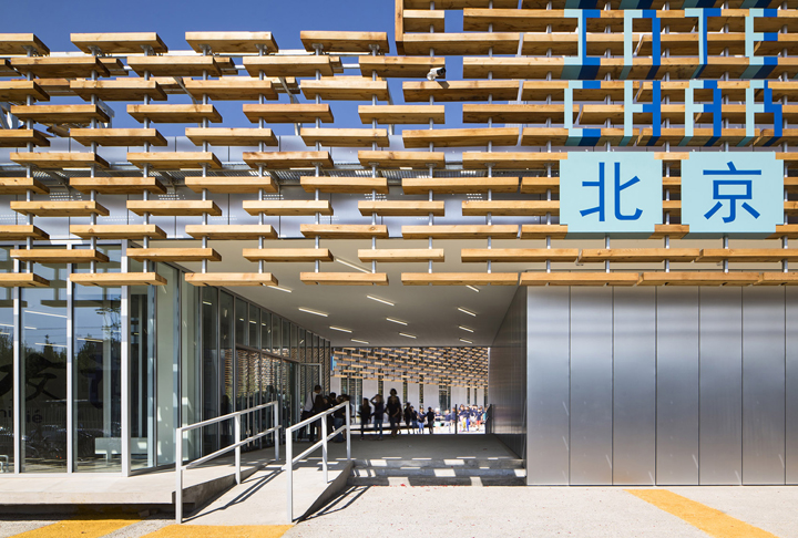 北京法国国际学校木格栅入口大厅内景,挂有北京标识,木质隔栅通透明亮,体现校园导视与文化设计