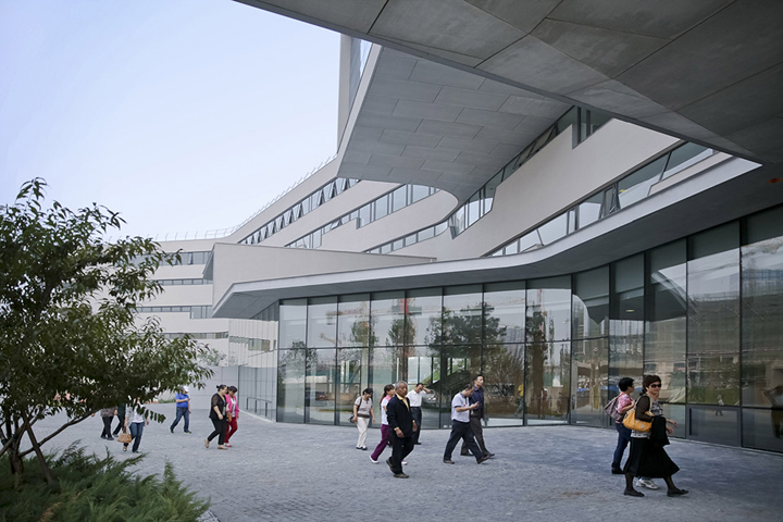 北京四中房山校区清水混凝土曲线建筑与学生活动场景,自然光线通透,展现绿色校园环境建设设计
