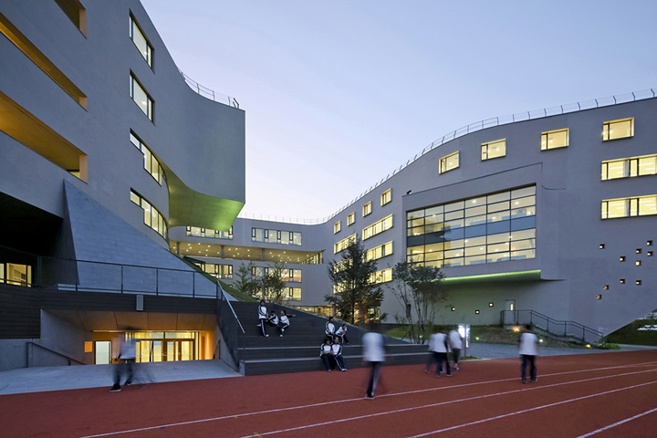 北京四中房山校区教学楼与运动跑道场景,建筑形态自然环保,呈现校园环境建设简约朴素的风貌