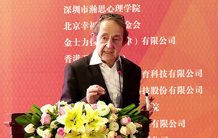 一位年长男嘉宾在积极心理学大会演讲台发言交流的现场场景