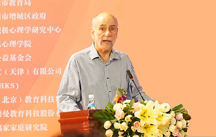 一位年长外籍专家在积极心理学大会演讲台发言的现场画面