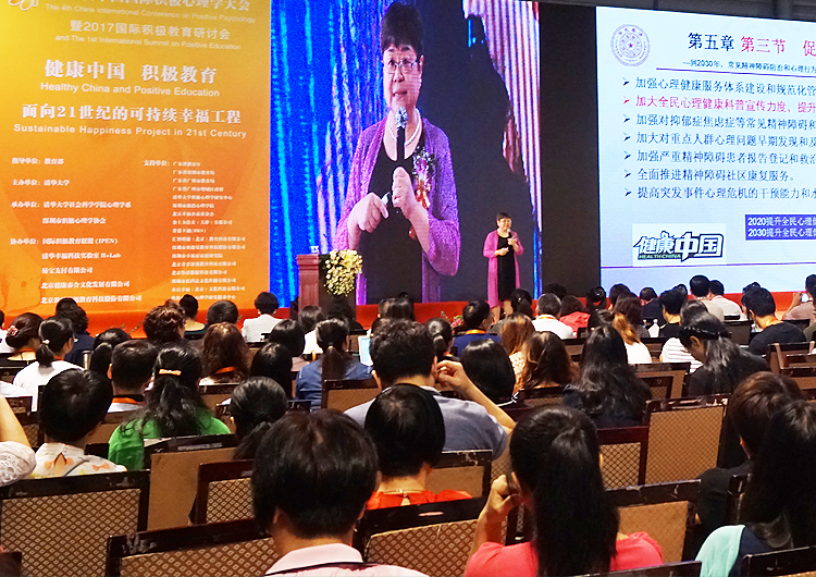演讲嘉宾在积极心理学大会舞台分享,大屏展示课程章节内容