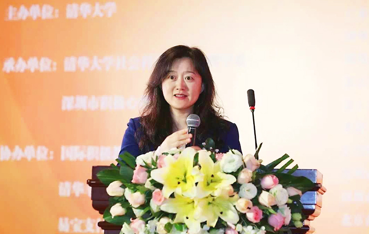 一位女主持人在积极心理学大会台上手持话筒发言介绍