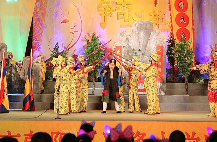 兴隆小学大型戏剧展演舞台,众多学生身着戏服在绚丽灯光中表演,呈现戏润文化教育特色
