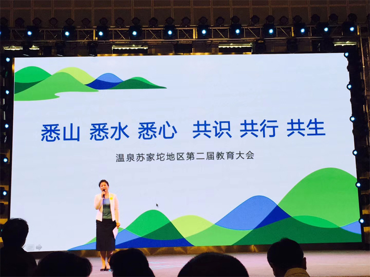 温泉苏家坨教育大会舞台,大屏呈现“悉山悉水悉心共识共行共生”主视觉,主持人登台