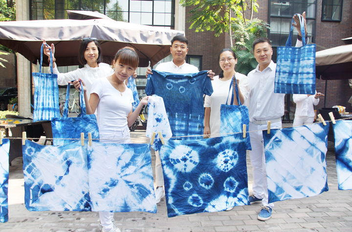 锦连环成员手举亲手制作的蓝白扎染作品合影，展示扎染成果