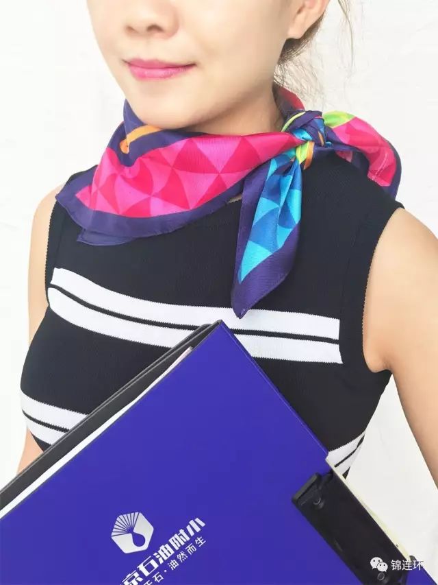 颈系石油附小彩色丝巾的女士手持印校徽蓝色文件夹,品牌VI物料展示