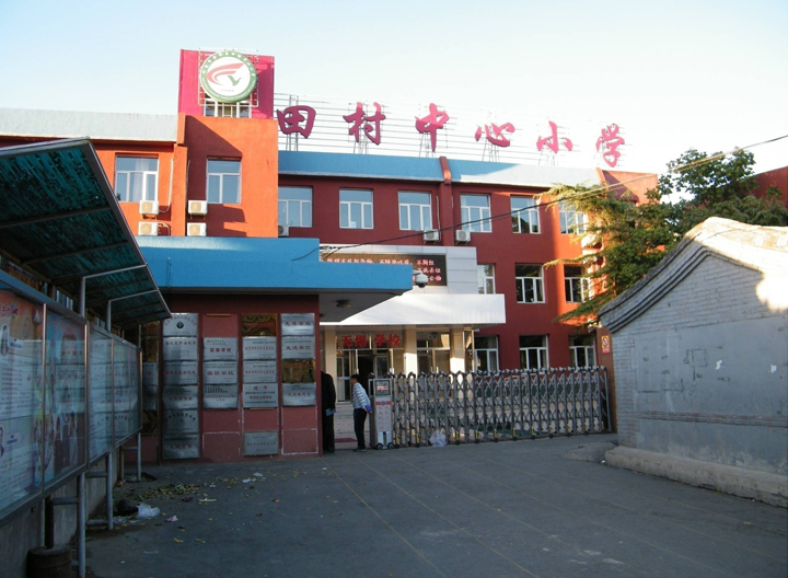 海淀区田村中心小学校门实景照片,红色教学楼前的校园入口环境面貌