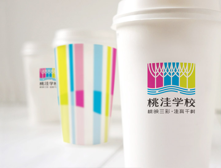 印有桃洼学校标识与彩色条纹的纸杯，校园品牌视觉在文创周边上的应用