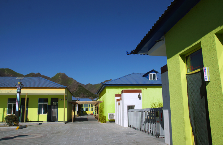 昌平南口山区桃洼学校绿色教学楼与远山蓝天,展现校园环境建设与山区校园自然风貌