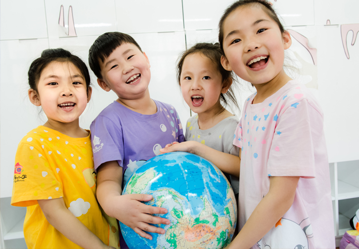 红英小学四名学生笑容灿烂围抱地球仪，展现阳光教育下学生的快乐成长与校园文化氛围