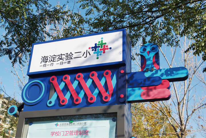 海淀实验二小校园入口立体品牌雕塑标志，蓝红加号造型展现教育品牌识别设计