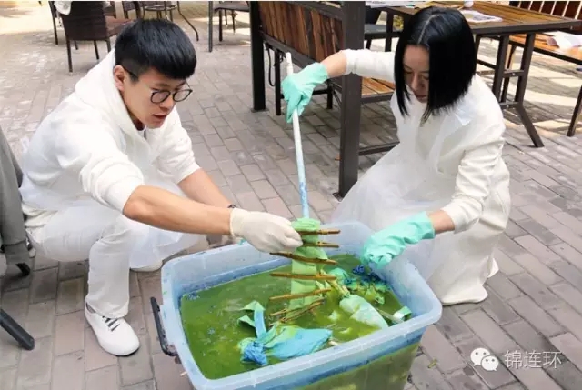 锦连环团队成员将布料投入蓝色染缸染色，文化之旅扎染手工体验活动现场