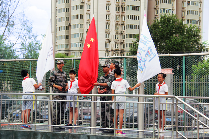 西二旗小学开学升旗仪式,学生与护旗手在升旗台举国旗校旗,锦连环旗趣文化校园活动现场
