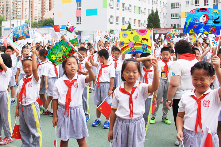 西二旗小学学生方阵手举彩色画作挥旗欢笑,开学典礼氛围热烈,锦连环旗趣文化校园文化建设