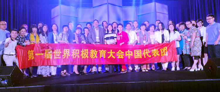第一届世界积极教育大会中国代表团在会场舞台手持红色横幅合影留念