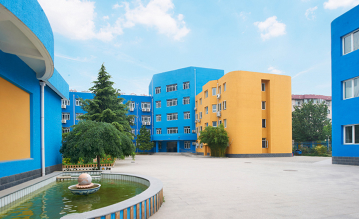 北京丰合第五小学校园实景,蓝橙相间教学楼与中心庭院水池,整体校园环境建设面貌